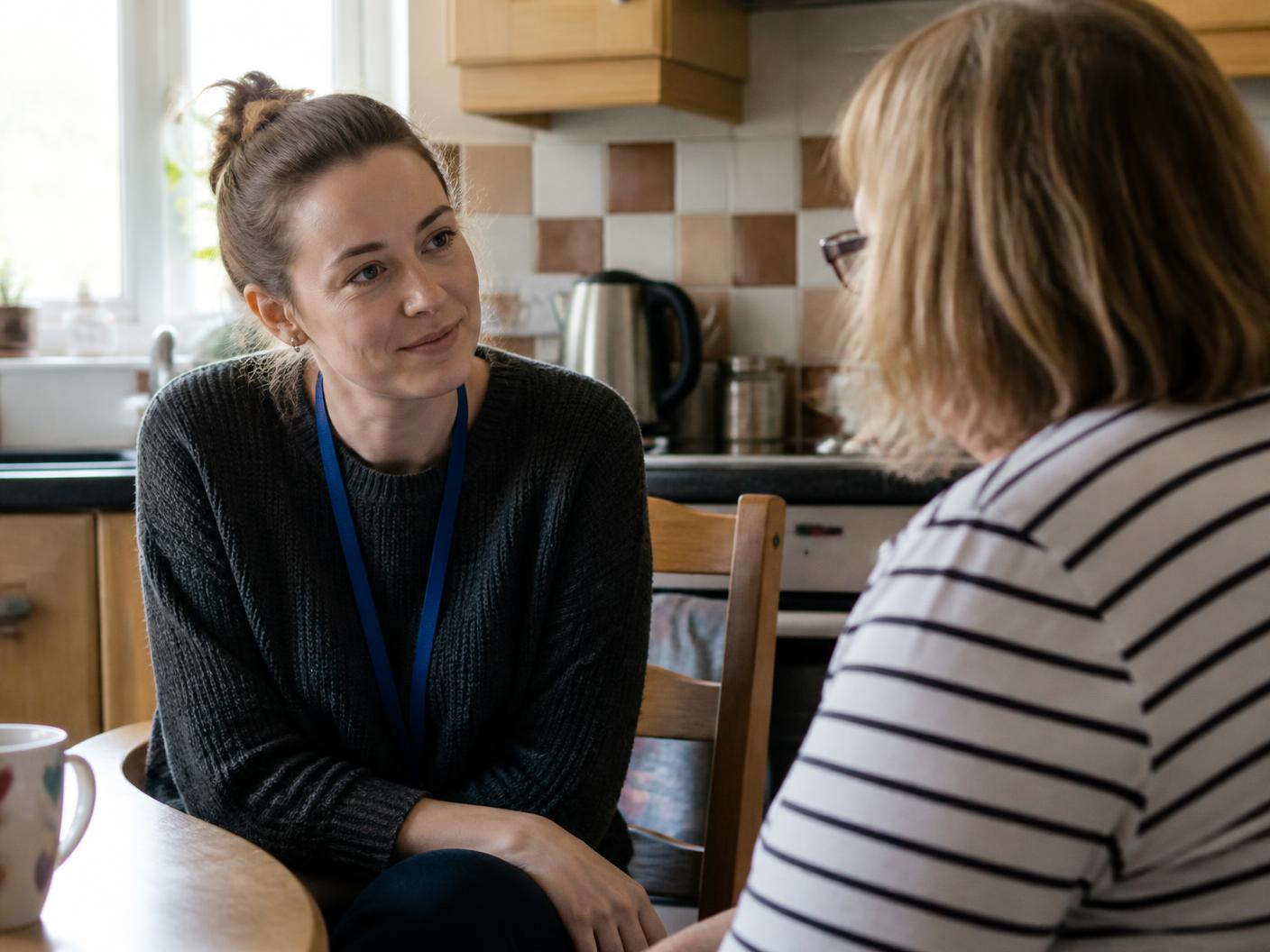 A support worker listening to a person in their kitchen
